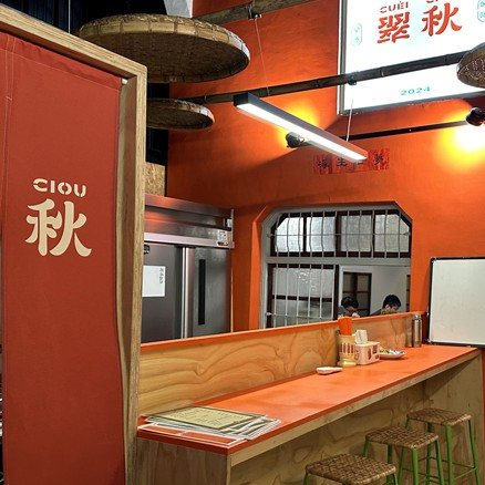 翠秋 CueiCiou 店內招牌橘色吧台與印有品牌字樣的暖簾