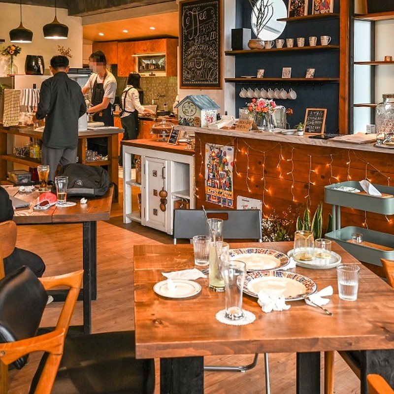 找一個地方 gotoaplace 木質餐桌上擺好的餐點餐盤，後方是暖色吧台與手寫菜單黑板實拍