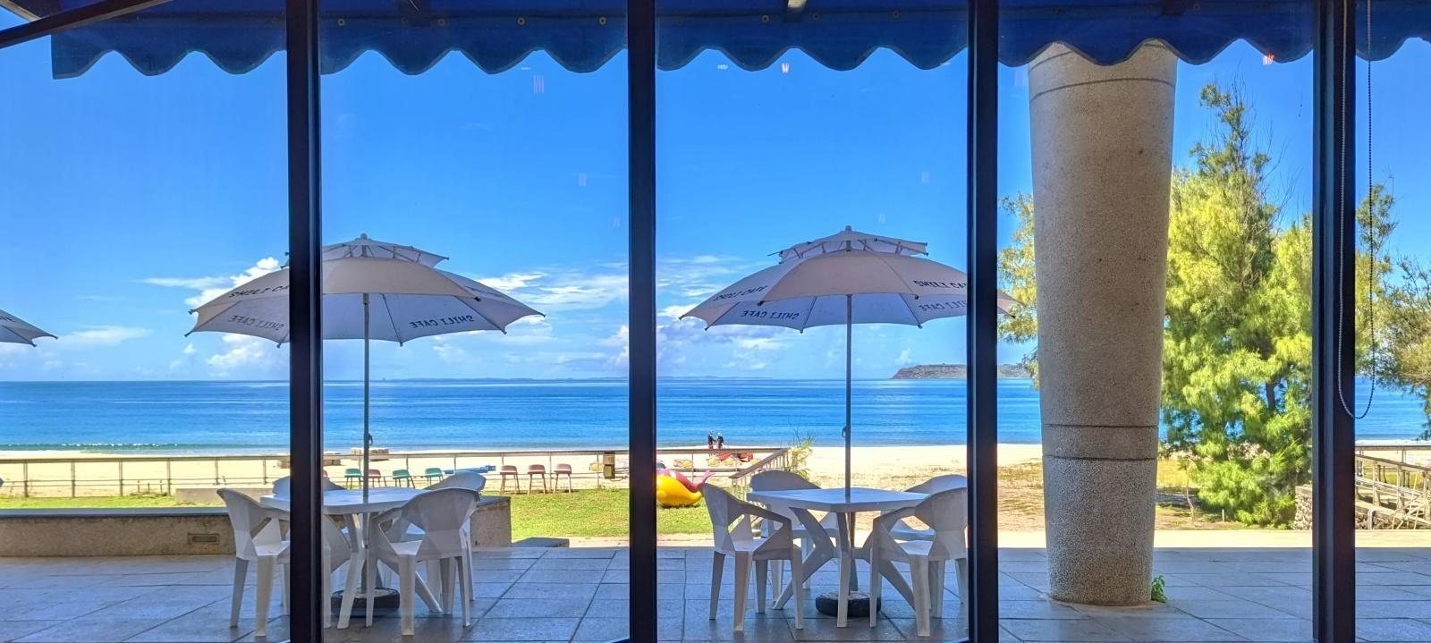 時咖啡 SHILICAFE 落地玻璃窗望出去,遮陽傘與大海連成一片的海景座位區